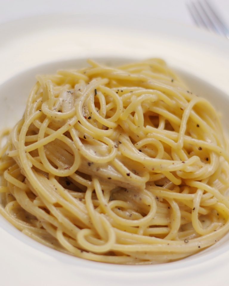 A plate of cacio e pepe pasta topped with cheese and black pepper
