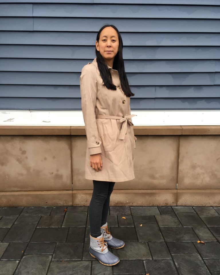 A person wearing a classic beige trench coat on a city street